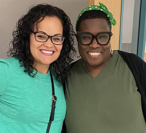 photo of two staff members wearing green