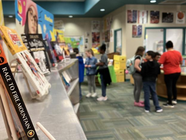 Books and students standing in the background for the 2023 Spring Book Fair